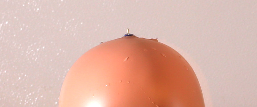 Encourage water balloon to burst by drawing pins